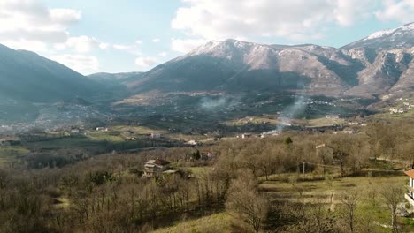 Aerial-landscape-view-over-mountain-villages,-on-a-sunny-day,-in-Italy