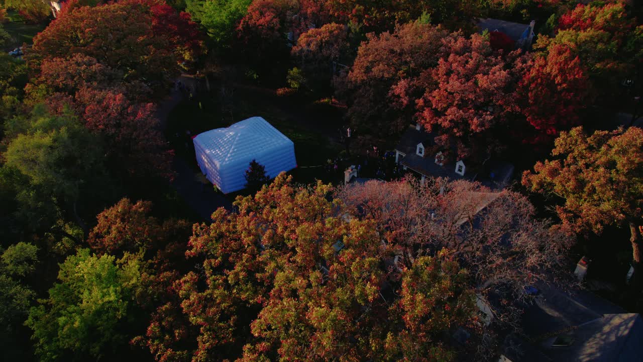 Aerial view of an inflatable tent set up for a home party surrounded by fall foliage in an American neighborhood.