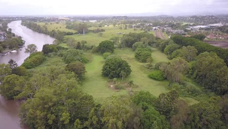 Umgekehrte-Luftaufnahme-Des-Von-Bäumen-Umgebenen-Golfplatzes-In-Der-Nähe-Des-Flusses-Nerang-In-Ashmore,-Queensland,-Australien