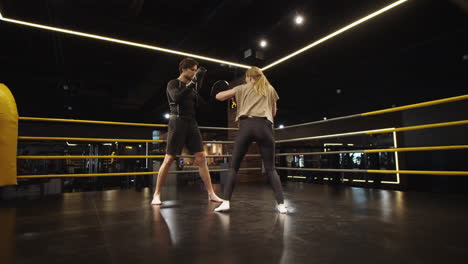 Chica-En-Forma-Seria-Peleando-Con-El-Entrenador-En-El-Gimnasio.-Entrenamiento-De-Pareja-Deportiva-En-Club-Deportivo.