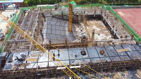 Aerial-drone-tilt-down-view-of-construction-cranes-at-building-site