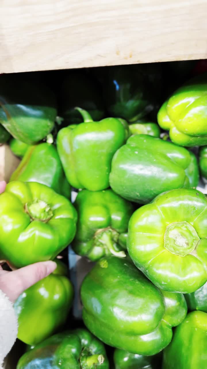 Hand holding a green bell pepper in a grocery store