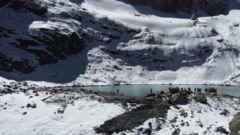 aerial: tourists visit laguna charquini in snowy mountains of bolivia