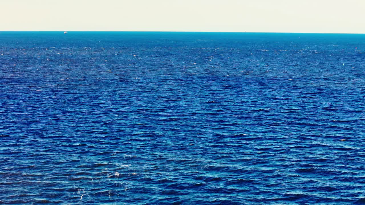 Calm, rippling deep blue sea expands toward the horizon under a soft sky, capturing the simplicity and vastness of open water in natural light.