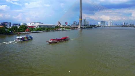 tourist boats sailing across the canals of chao phraya river near the rama viii bridge in bangkok, thailand