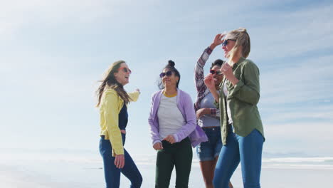 un grupo feliz de amigas diversas divirtiéndose, bailando y sonriendo en la playa