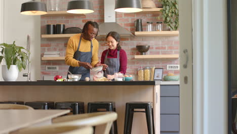 happy diverse couple in aprons baking in kitchen, copy space, slow motion