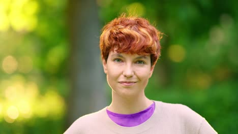 portrait of a smiling woman with short red hair outdoors
