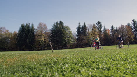 Couple-enjoying-a-rural-area-scenery-while-cycling-on-a-country-road,-dolly-left