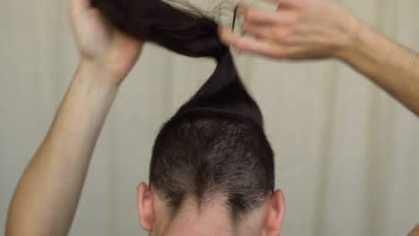 Man-undoing-his-man-bun-hair-style-from-behind