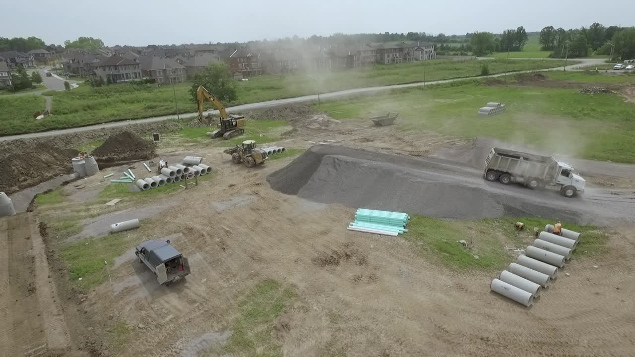 Aerial of dump truck backing up a gravel ramp to unload gravel