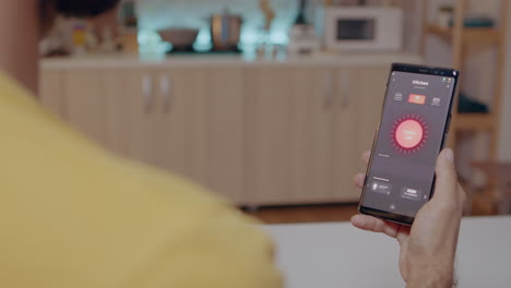 Man-sitting-in-house-with-automation-light-system-holding-smartphone