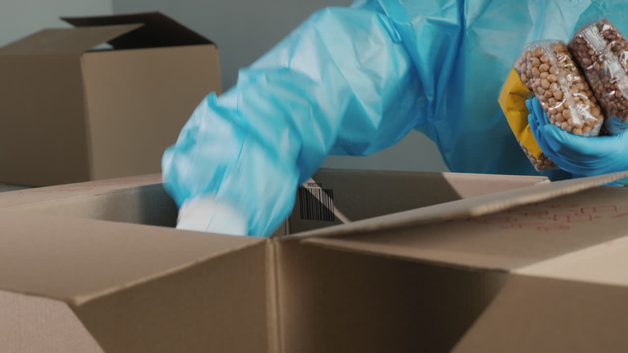 보호복을 입은 남자가 장기 저장 제품을 상자에 넣습니다.