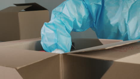 a man in a protective suit puts long-store products in a box