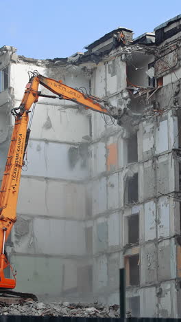 demolition of the old multi flat house. house being demolished by special machinery.