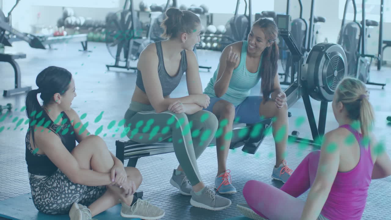 In gym, women chatting while animated fitness data overlay displays on screen