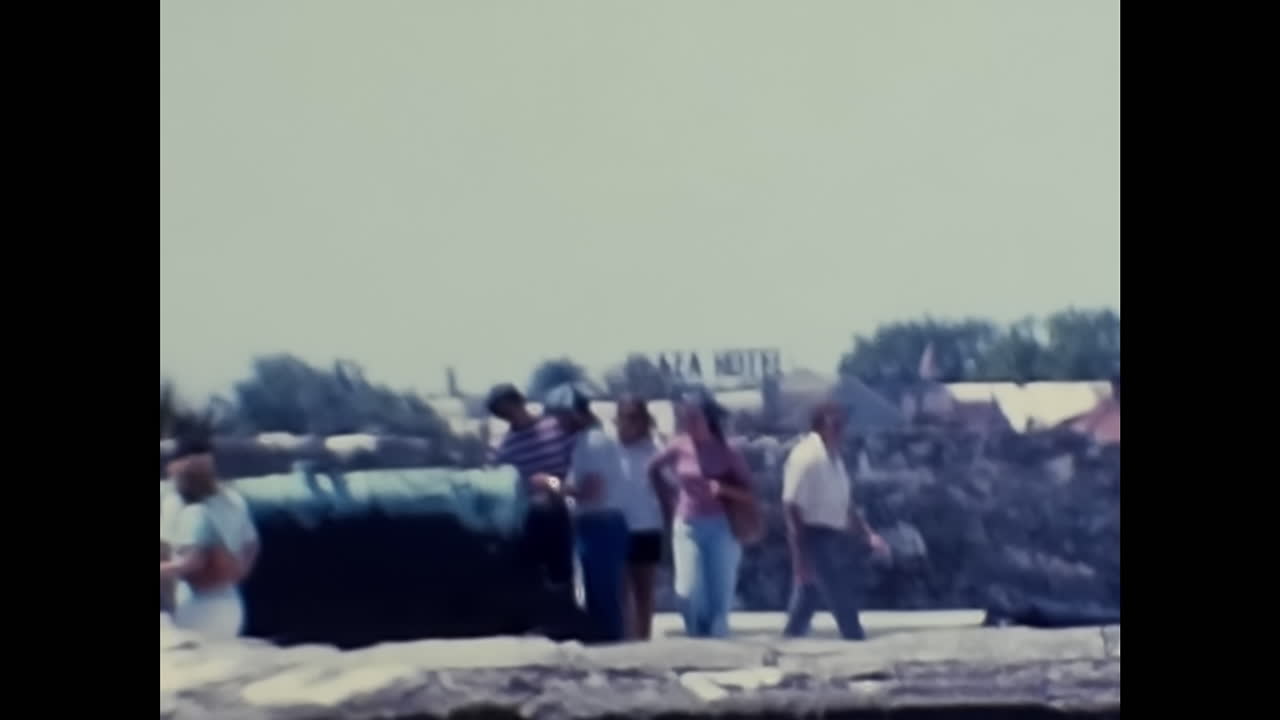 People Standing Next to Each Other Near a Stone Wall in 1970s USA. CIRCA USA - 1970s: An archive video capturing individuals standing beside each other in close proximity to a stone wall during the 1970s in the United States.