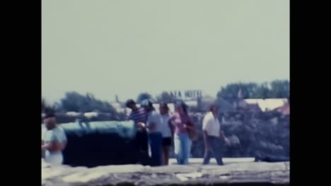 people standing next to each other near a stone wall in 1970s usa. circa usa - 1970s: an archive video capturing individuals standing beside each other in close proximity to a stone wall during the 1970s in the united states.