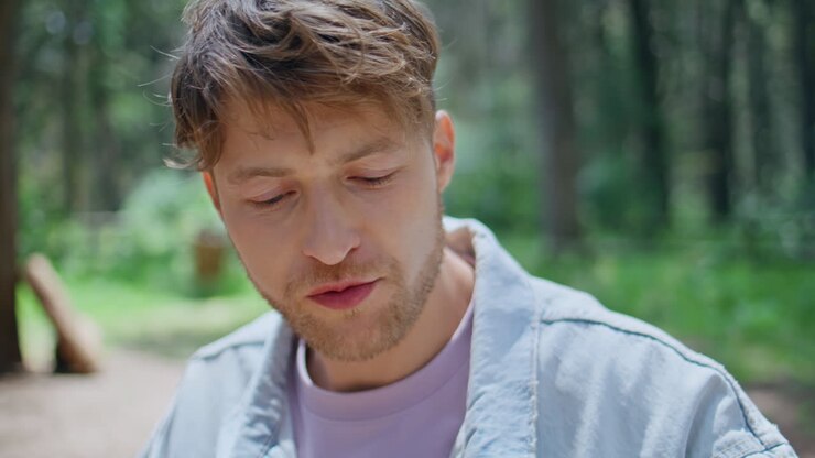Man drinking beer picnic in sunlit forest closeup. Portrait relaxed guy relaxing
