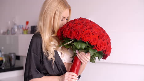mujer feliz en camiseta sosteniendo un ramo de rosas rojas