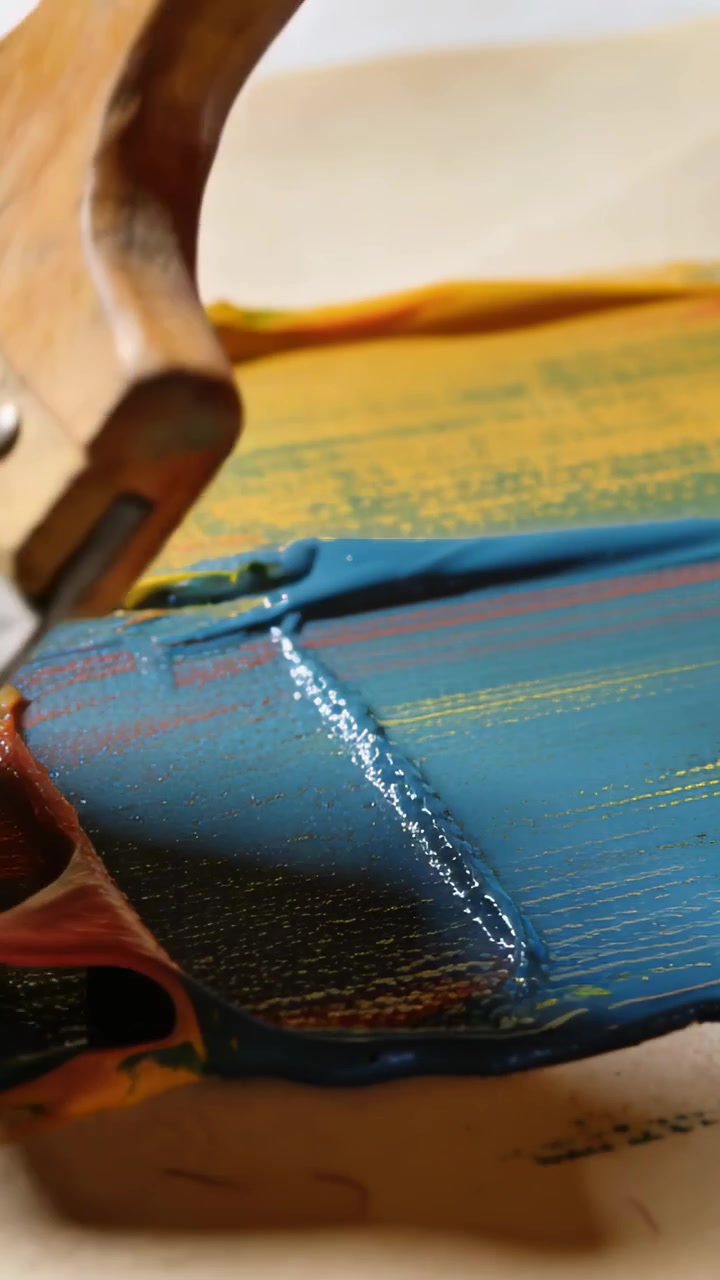 Video verticale: Tirando un pennello di legno dal retro, si stende vernice arcobaleno levigando le creste in studio.