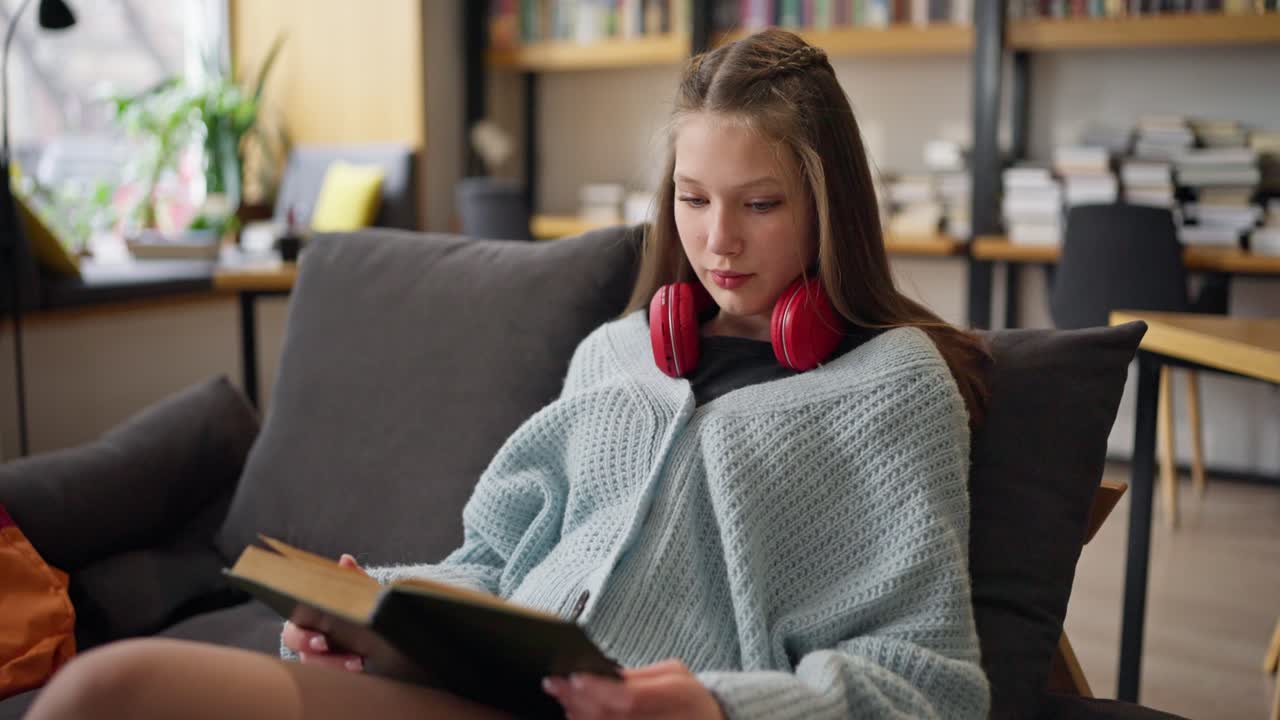Adolescent lisant un livre dans un café de bibliothèque douillet