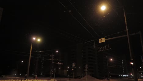calle oscura por la noche durante las nevadas con luces rojas intermitentes