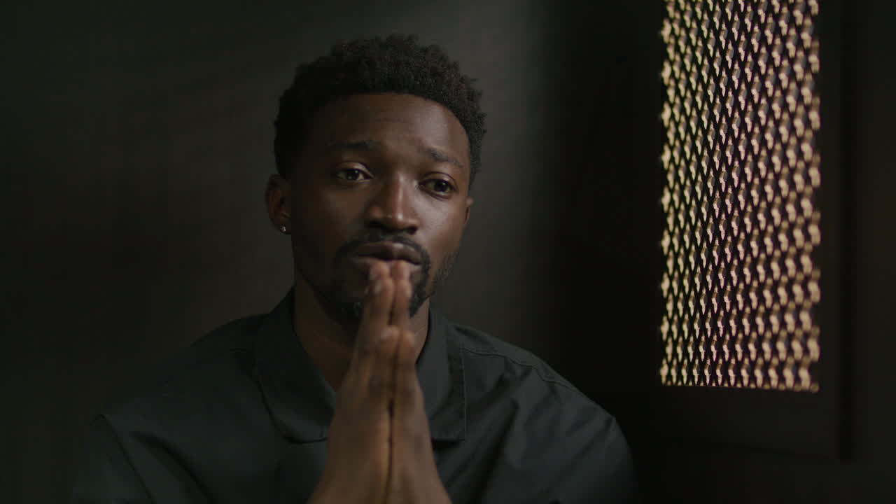 African American Man Praying to God in Confessional Booth