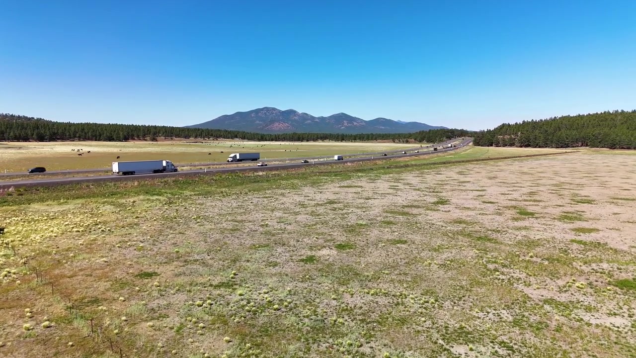 Bright aerial drone shot capturing bustling traffic on two parallel American highways crossing through a vast green prairie landscape