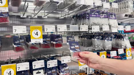 persona que elige aparejos de pesca de la exhibición de la tienda