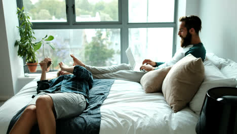 couple using laptop and mobile phone on bed 4k