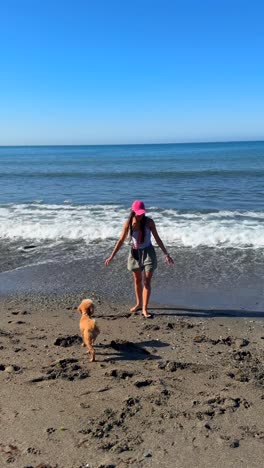 mujer y perro jugando en la playa