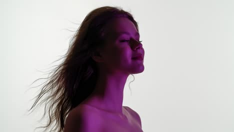 young woman with hair blowing in purple light