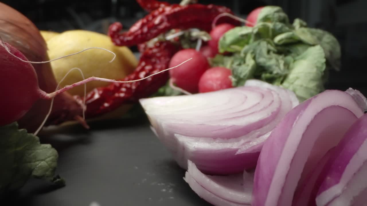 A probe-macro lens captures radishes, peppers, purple onion and lemons on a rustic wood table