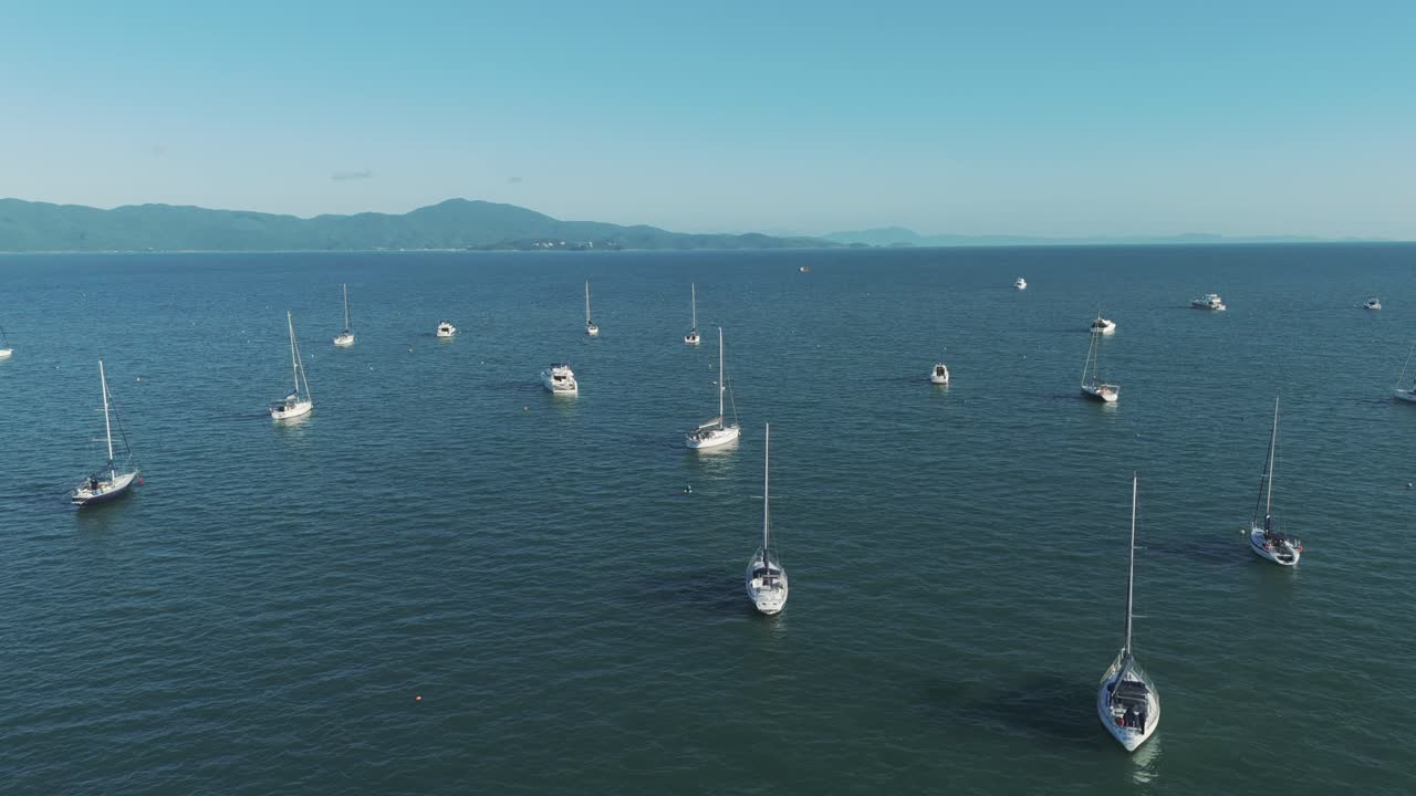 vista aérea de varios barcos anclados a lo largo de la costa brasileña en un hermoso día de sol y aguas tranquilas