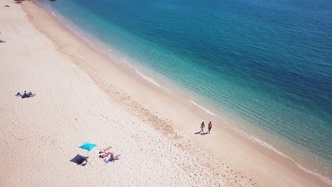 aerial view couple walking near cristal clear water in arrábida, portugal