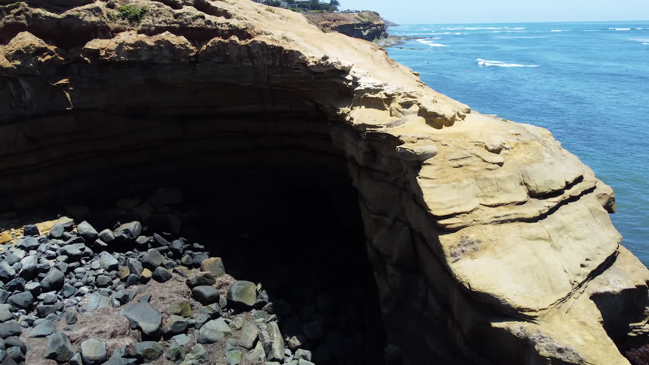 océano azul y cueva de acantilados al atardecer, vista de órbita aérea