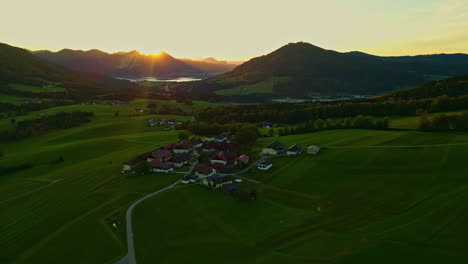 aerial drone pan shot from left to right over small village surrounded by mountain range in norway with sunrise in the background