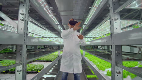 scientists a man in a white lab coat use glasses virtual reality in the farm with the hydroponics for irrigation control. geneticists analyze the composition of vegetables growing on plantations