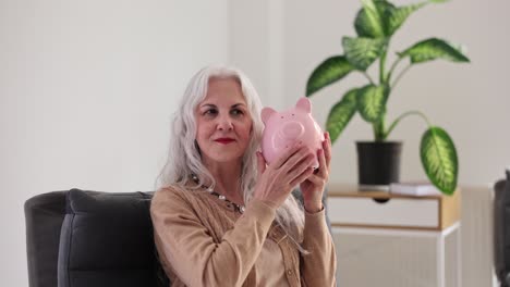 senior woman holding a pink piggy bank