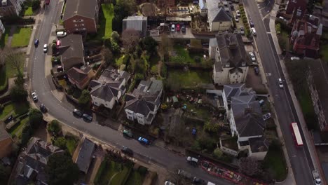 Wide-aerial-pan-up-reveal-from-houses-in-Subiton,-London,-UK-to-reveal-the-train-station-and-horizon