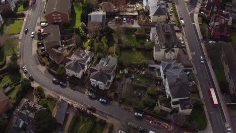 wide aerial pan up reveal from houses in subiton, london, uk to reveal the train station and horizon
