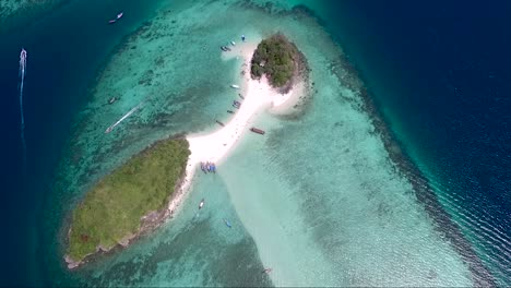 thrilling aerial shot over a small tropical island surrounded by beautiful turquoise water