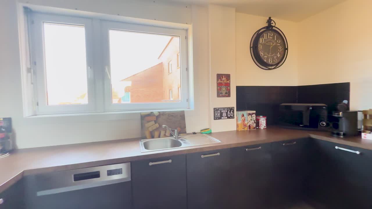 A sunlit, stylish kitchen with retro and vintage elements, modern appliances, and antique decor. Smooth camera pan reveals open layout, cozy seating, and decorative details