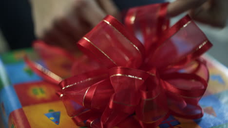 mujer colocando un lazo rojo en un regalo de navidad envuelto, de cerca, de mano