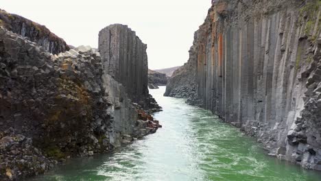 aerial view of fast streaming water through a steep canyon in iceland-