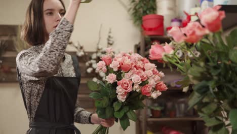 florist arranging a bouquet of pink roses