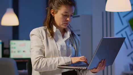 manager woman holding laptop, typing and looking satisfied at camera