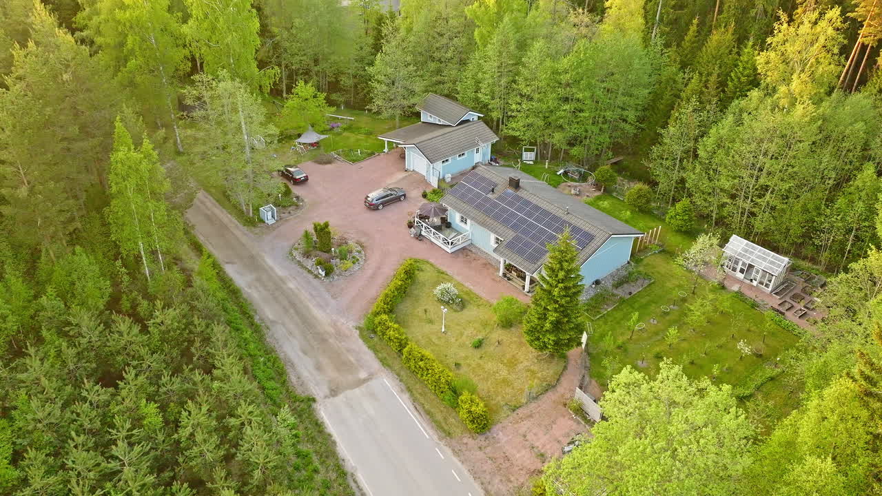 LUFTFOTO: Solcelledrevet hus midt i nordiske skovområder, sommersolopgang.