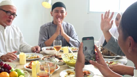 family muslim gather around dining table capturing happy moment on smartphone